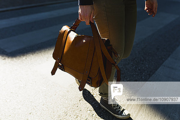Woman carrying leather bag  partial view