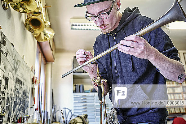 Instrument maker making trumpet in workshop
