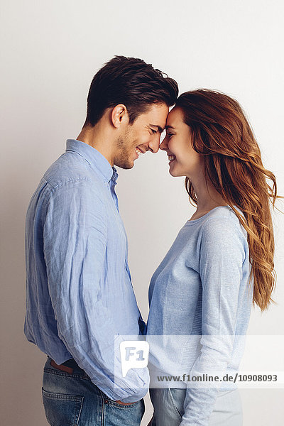 Happy young couple standing face to face in front of white background