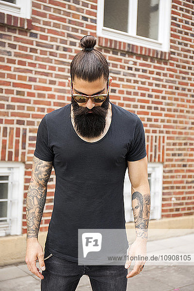 Portrait of young man with full beard  bun and tatooed arms