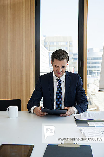 Portrait of businessman at office desk looking at folder