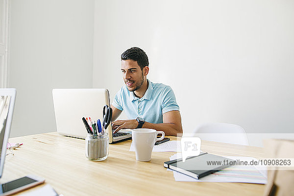 Young man working in office using laptop