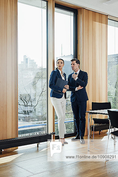 Businessman and businesswoman in office talking at the window
