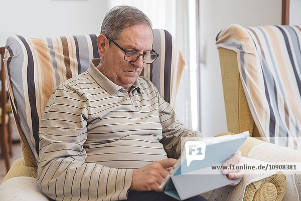 Senior man at home using digital tablet