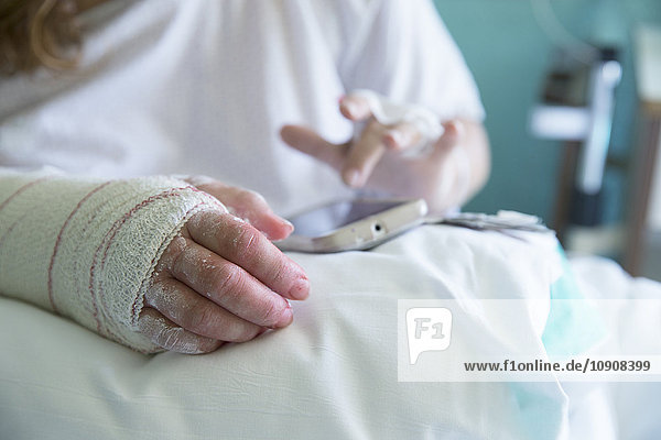 Frau im Krankenhaus  operierte Hand  mit Handy  linke Hand