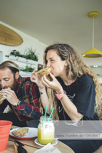 Couple having breakfast in cafe  eating sandwiches and organic juices