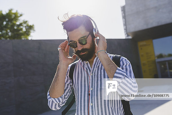 Bearded young man with sunglasses listening music with headphones