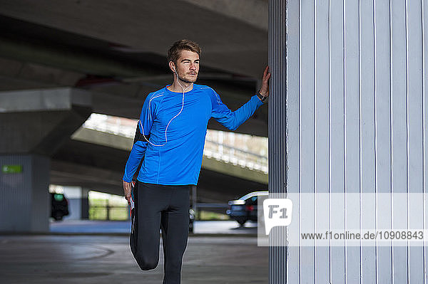 Young sporty man stretching smartwatch and headphones