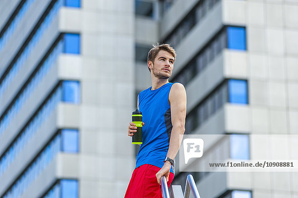 Junger sportlicher Mann mit Wasserflasche und Smartwatch