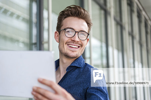 Portrait of smiling young businessman with digital tablet