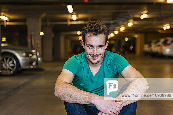 Portrait of smiling young man sitting in underground car park