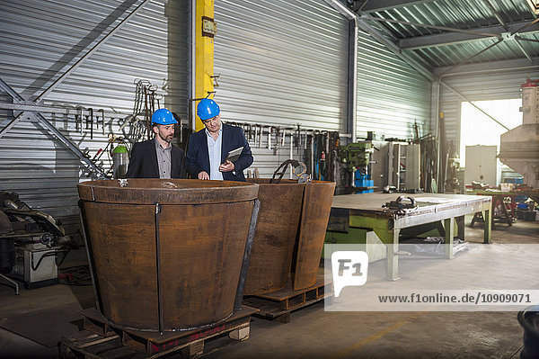 Manager with digital tablet in front of steel tank