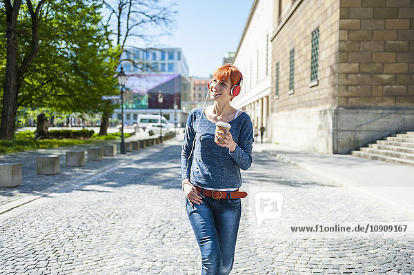 Lächelnde junge Frau mit Kaffee zum Musikhören