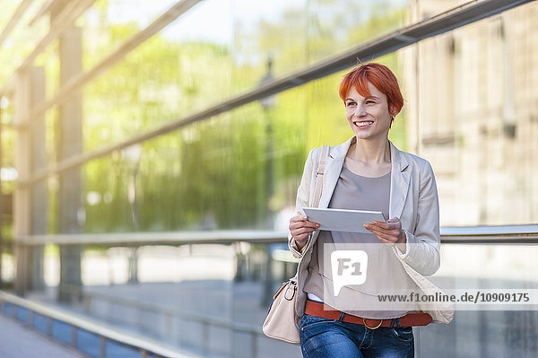 Lächelnde junge Frau im Freien mit digitalem Tablett