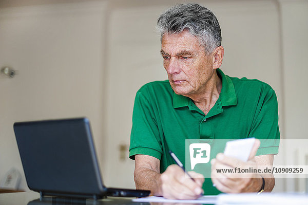 Senior Mann sitzt am Schreibtisch mit Laptop