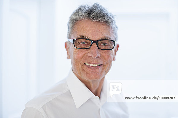 Portrait of smiling senior man wearing glasses and white shirt