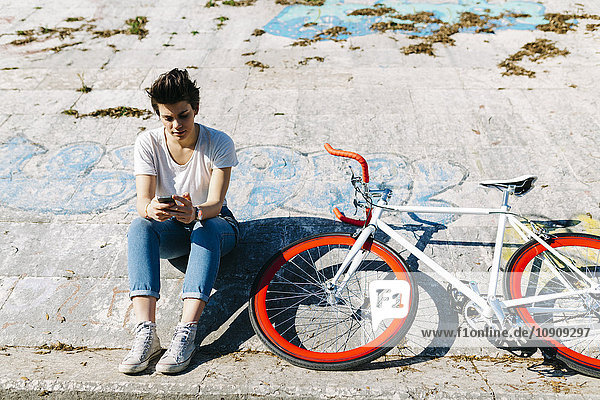Junge Frau mit Fahrrad und Handy