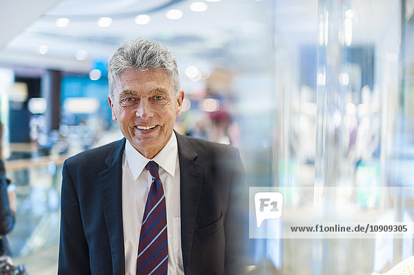 Portrait of smiling senior man at shop window