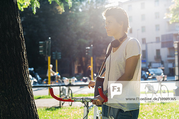 Junge Frau mit Fahrrad im Park