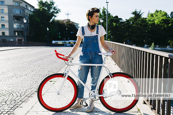 Junge Frau mit Fahrrad auf Brücke