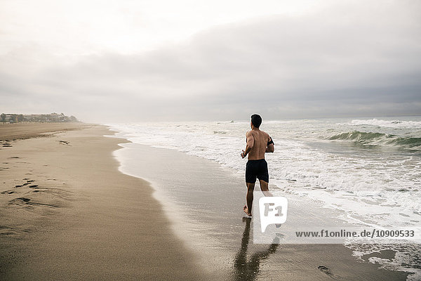 Junger Mann  der am Strand rennt.