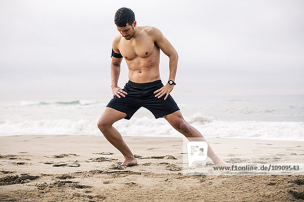 Sportlicher junger Mann  der sich am Strand ausstreckt