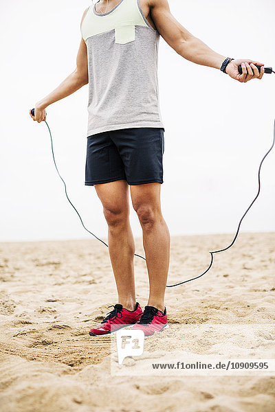 Young man skipping rope on the beach