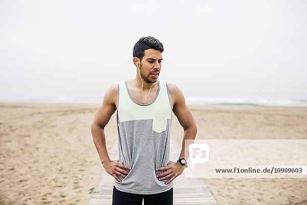 Portrait of athlete with earbuds on the beach