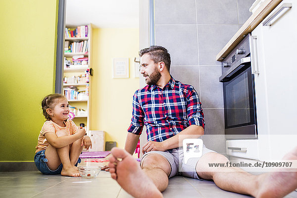 Vater und Tochter essen Tomaten in der Küche