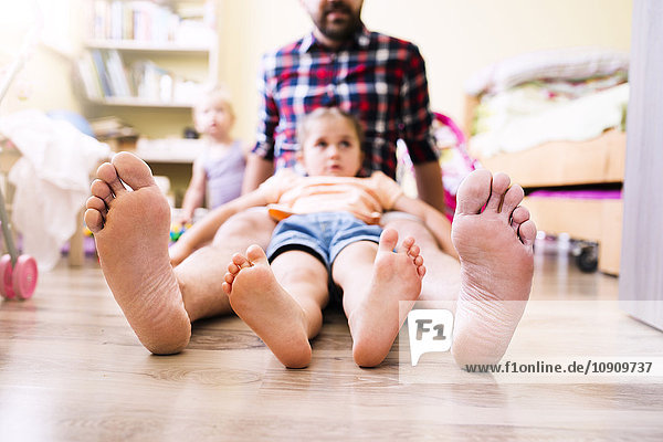 Vater und Tochter zu Hause die ihre nackten Füße zeigen.