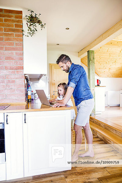 Vater und Tochter mit dem Laptop zu Hause