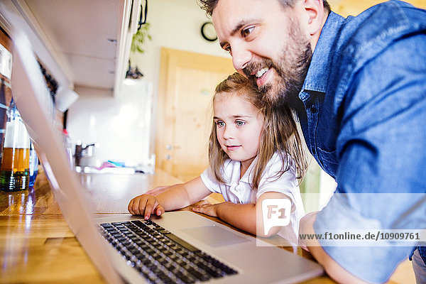 Vater und Tochter mit dem Laptop zu Hause