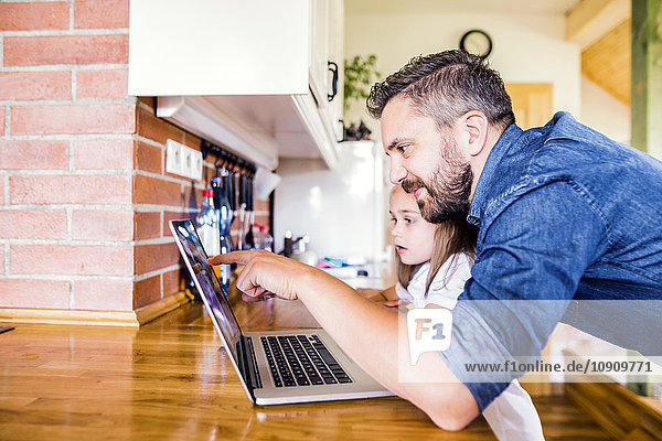 Vater und Tochter mit dem Laptop zu Hause