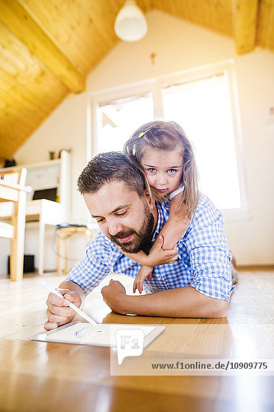 Vater und Tochter auf dem Boden liegend Zeichnung auf digitalem Tablett