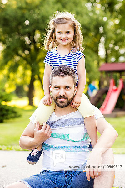 Portrait of father with little daughter on his shoulders