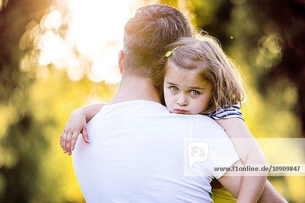 Porträt eines traurigen kleinen Mädchens auf den Armen des Vaters