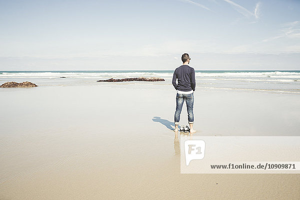 Spanien  Ribadeo  Junger Mann am Strand von Las Catedrales an einem Frühlingstag