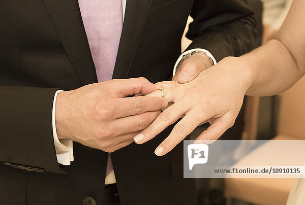 Bräutigam legt Ehering auf Brauthand
