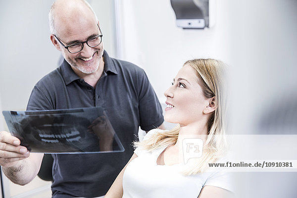 Dentist showing x-ray image to patient  sitting in dentist's chair