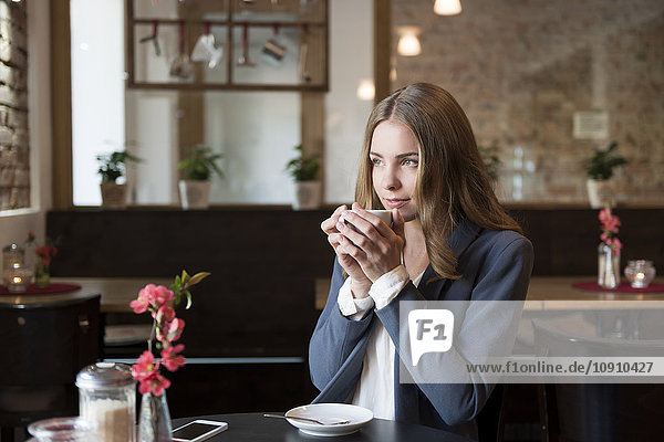 Portrait of young woman drinking coffee in a coffee shop