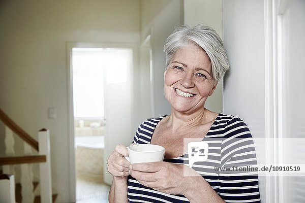 Porträt der lächelnden Frau mit Tasse Kaffee zu Hause