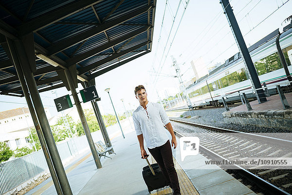 Young man with suitcase walking at station platform