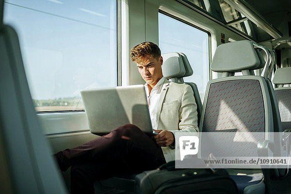Young man using a laptop on a train