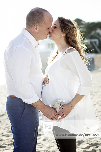 Spain  Majorca  pregnant woman kissing man on beach