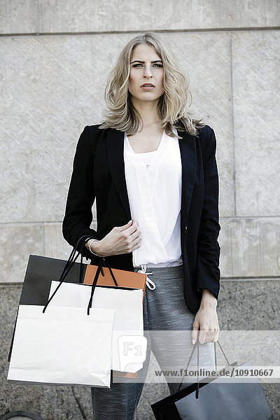 Porträt einer ernsthaft aussehenden Frau mit vielen Einkaufstaschen