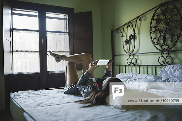 Woman lying in bed using smartphone