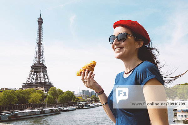 Frankreich Paris Frau mit Croissant vor der Seine und Eiffelturm