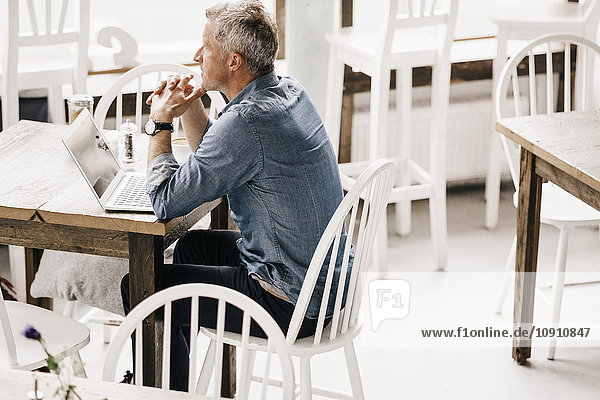 Erwachsener Mann sitzt im Cafe mit Laptop
