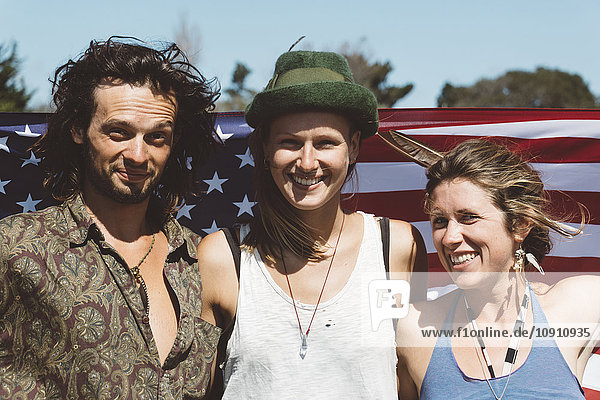 Portrait of three smiling hippies with US flag