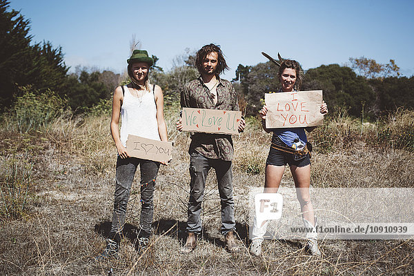 Three hippies holding 'I love you' signs in the nature